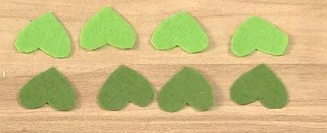 在不织布上按照模板剪出深绿色心形4片、草绿色心形4片。